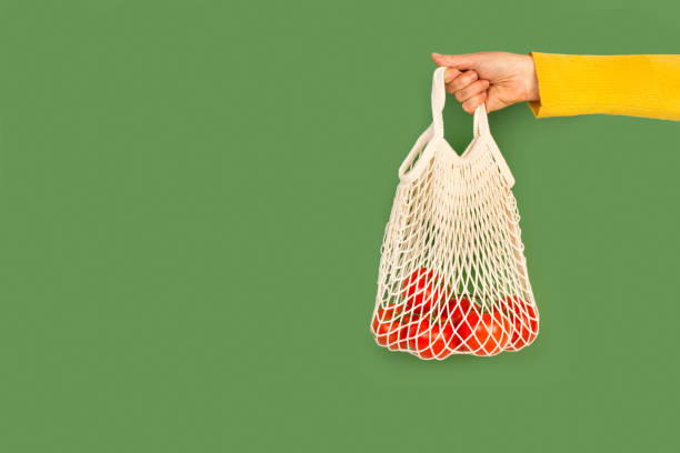 istock Woman hand holding a cotton mesh bag with red tomatoes 1306483852