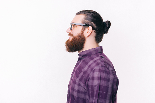 Side view portrait of young bearded man wearing eyeglasses.