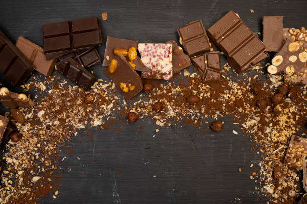 istock Many different types of chocolate and various ingredients such as nuts and cocoa powder lie on a black wooden plate