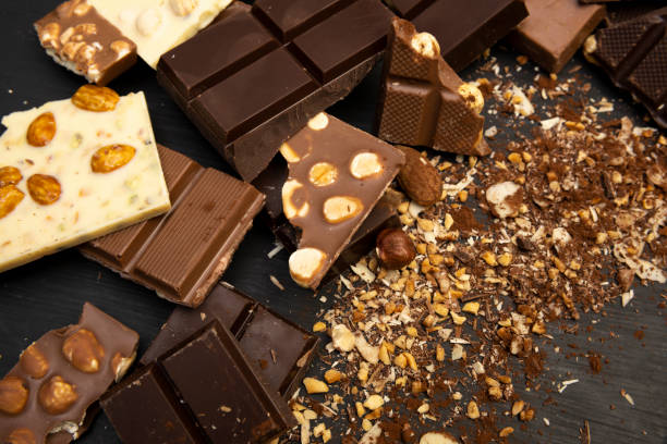 istock Many different types of chocolate and various ingredients such as nuts and cocoa powder lie on a black wooden plate