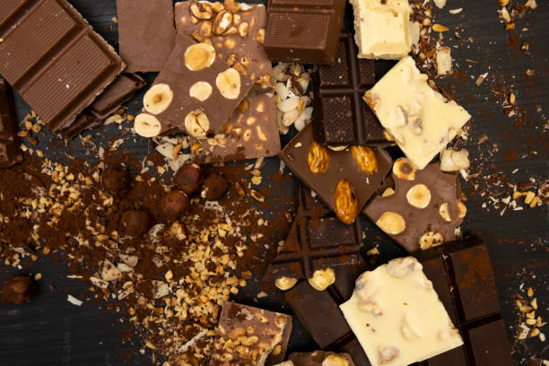 istock Many different types of chocolate and various ingredients such as nuts and cocoa powder lie on a black wooden plate
