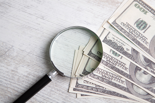 Hundred dollar bill and magnifying glass