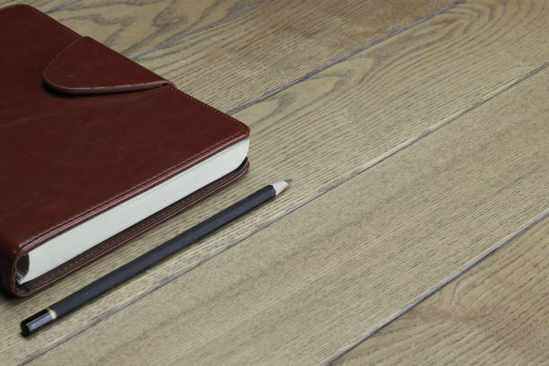 istock a closed notebook in a leather cover with a pencil lies on a wooden table without people background image 1306488708
