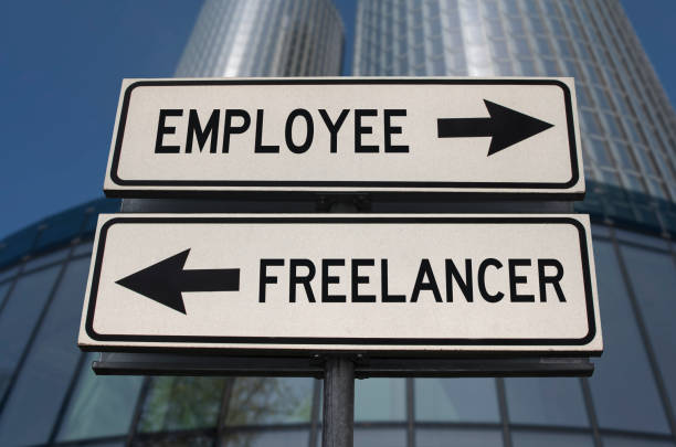 Employee versus freelancer road sign with two arrows on business skyscraper background. White two street sign with arrows on metal pole. Two way road sign with text. stock photo