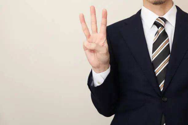 Photo of A man in a suit with three fingers