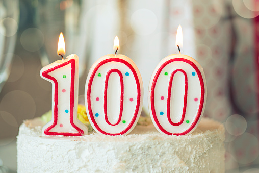Vela de cumpleaños como número cien en la parte superior de pastel dulce en la mesa, 100 cumpleaños photo
