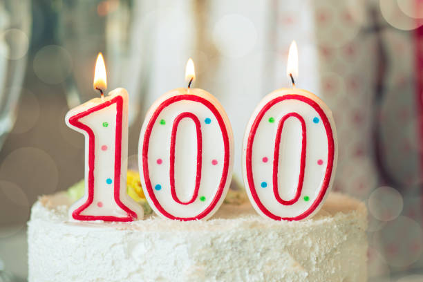 テーブルの上の甘いケーキの上にナンバーワン百、100歳の誕生日として誕生日キャンドル - 100th anniversary ストックフォトと画像