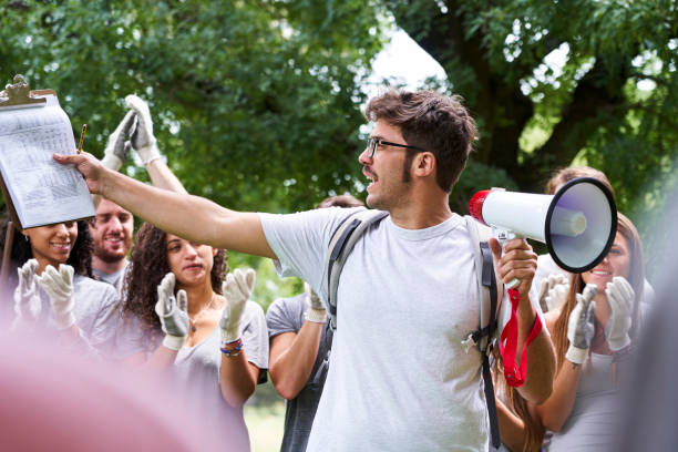 istock Male volunteer looking at clipboard while talking on megaphone in park 1306495178