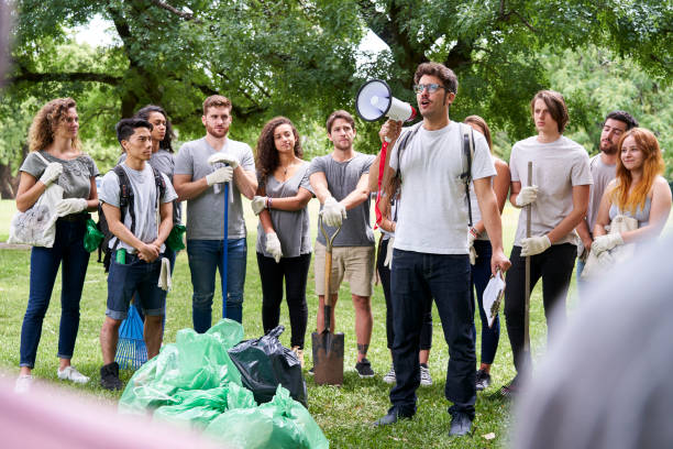 istock Male volunteer talking on megaphone while standing with his friends in park 1306495193