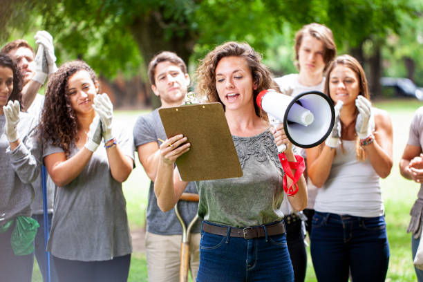 istock Young female activist holding megaphone and reading from clipboard during garbage cleanup event 1306495363