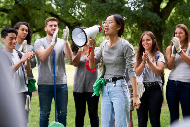 istock Young female volunteer talking on megaphone while standing with environmental activists in park 1306495591