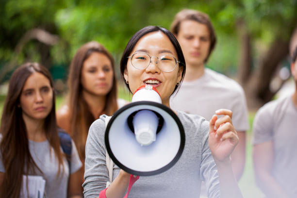 istock Young female volunteer talking on megaphone in park 1306495637