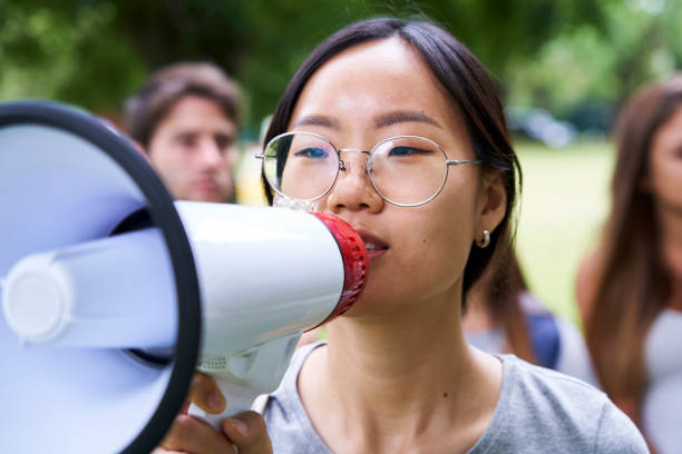 istock Young female volunteer talking on megaphone in park 1306495661