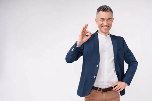 Photo of Good-looking caucasian mature businessman showing okay sign isolated in white background