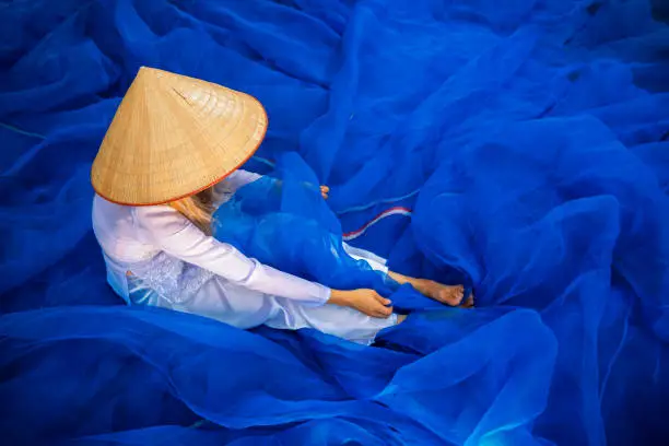 Photo of Vietnamese girls are cleaning fish trap mesh. fisherman pull fish net. Traditional and culture of Asian woman repairing fishing nets in home. Vietnam, Asia.
