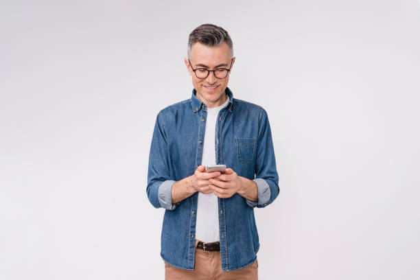 istock Handsome caucasian mature man in casual clothes using mobile phone isolated over white background 1306498644