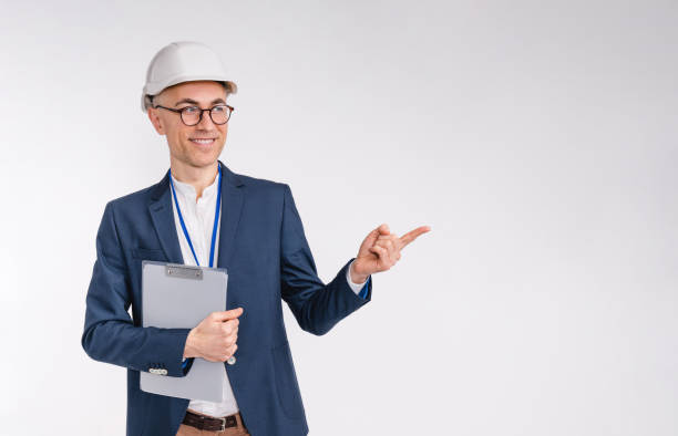 istock Handsome middle-aged white engineer in hardhat pointing at copy space isolated over white background 1306498841