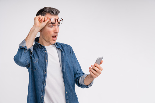 Surprised mature caucasian man using smart phone isolated over white background