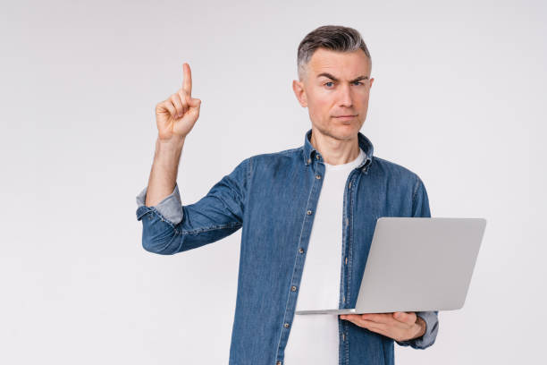 istock Serious handsome middle-aged man having an idea with laptop isolated over white background 1306500165