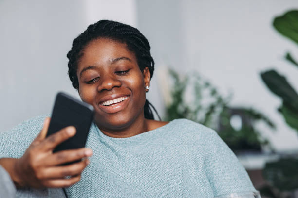 istock Women in Business: A Smiling Young Businesswoman Using a Mobile Phone while Working from Home 1306500247
