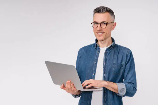 Confident good-looking mature man using laptop isolated over white background