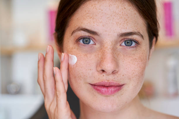 istock Smiling young woman applying cream on her face 1306502006