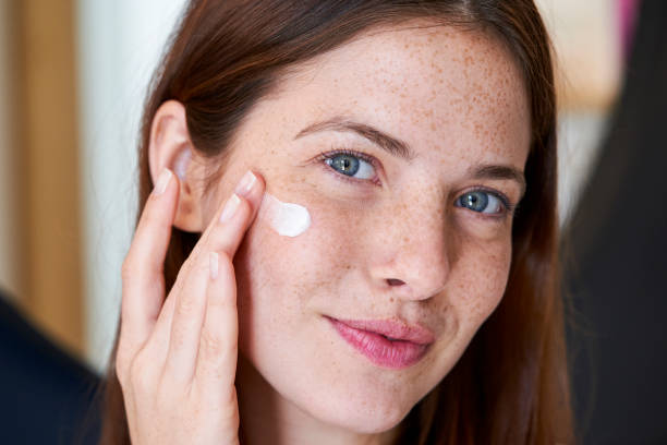 istock Smiling young woman applying cream on her face 1306502068