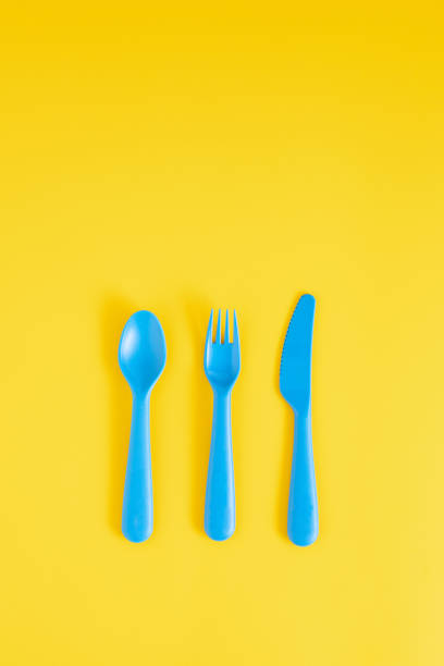 istock Blue spoon, fork and knife on a bright yellow background with copy space. Flat lay minimal concept. 1306502563