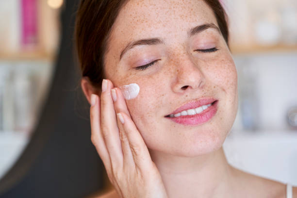 istock Smiling young woman with eyes closed applying cream on her face 1306502690