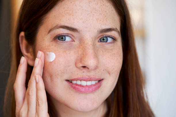 istock Smiling woman applying cream on her face 1306502737