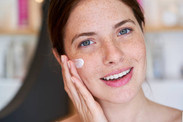 istock Smiling woman applying cream on her face 1306502757