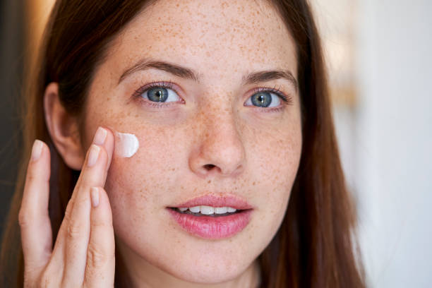 istock Smiling young woman applying cream on her face 1306502830