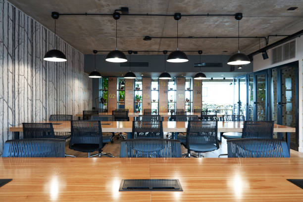 istock Interior view of industrial office with long tables and chairs 1306503914