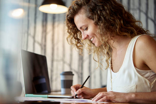 istock Smiling businesswoman writing on paper while sitting in office 1306505031