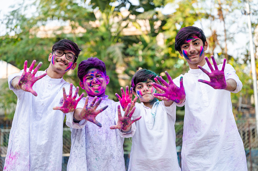 Outdoor image of a group of young boys playing Holi festival with colour powders in nature park. Concepts for Indian festival Holi with Indian boy in outdoor location. Holi is a religious festival in India, celebrated, with the color powders, during the spring.