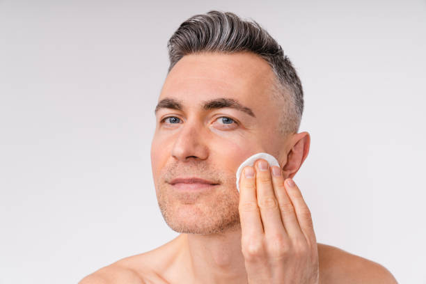 istock Attractive middle-aged man using cotton pad shirtless isolated over white background 1306506090