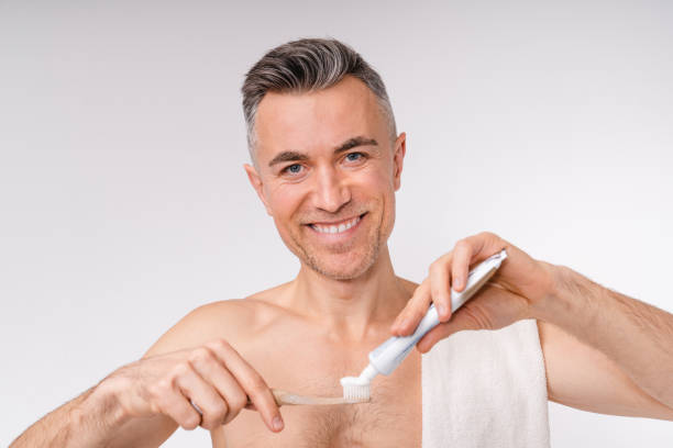 homme caucasien mûr beau se brossant des dents le matin d’isolement au-dessus du fond blanc - shower portrait male beauty chest photos et images de collection