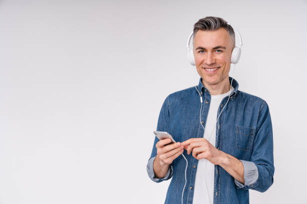 istock Confident middle-aged man choosing music track on phone isolated over white background 1306508580