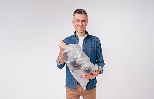 Eco-friendly caucasian man holding a bag full of plastic bottles isolated over white background