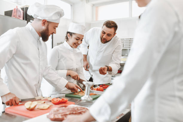 istock Chef Describing Vegetable Cutting Process to Smiling Female Student In Kitchen 1306510043