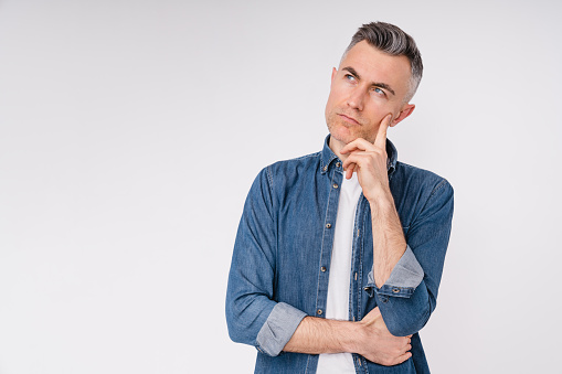 Pensive mature caucasian man in denim shirt isolated in white background