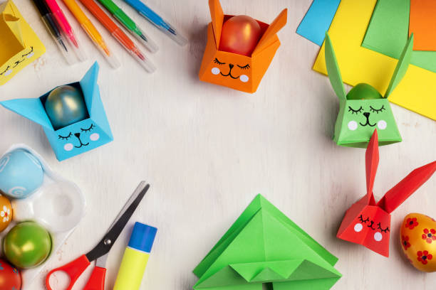 istock Cute Easter bunny made of paper. Children's handmade Easter craft. DIY and kids creativity. Step by step instruction: how to make origami paper egg basket for Happy Easter greetings. Top view. 1306510646