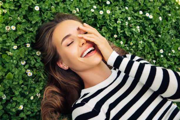 istock High Angle View Of Smiling Young Woman Lying Down On Grass 1306510874