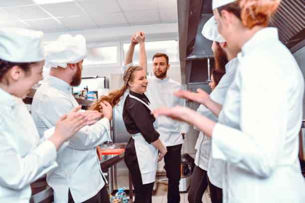 istock Smiling Cooks In Kitchen Encouraging Cook To Dance With Waitress 1306510875