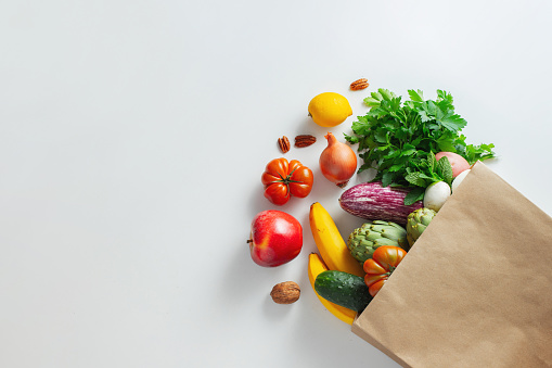 Antecedentes alimentarios saludables. Comida vegetariana vegana saludable en verduras y frutas en bolsas de papel en blanco, espacio de copia, banner. Supermercado de comida de compras y concepto de alimentación vegana limpia photo