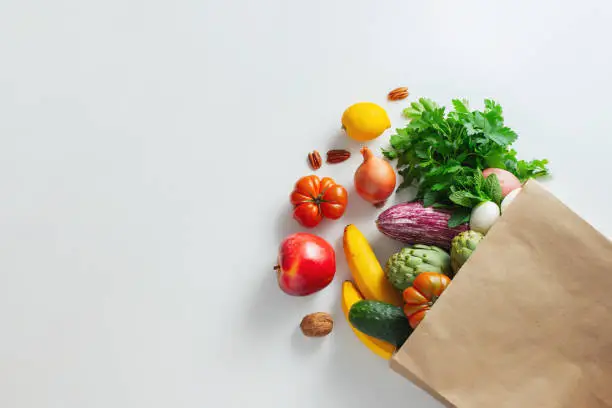 Healthy food background. Healthy vegan vegetarian food in paper bag vegetables and fruits on white, copy space, banner. Shopping food supermarket and clean vegan eating concept.