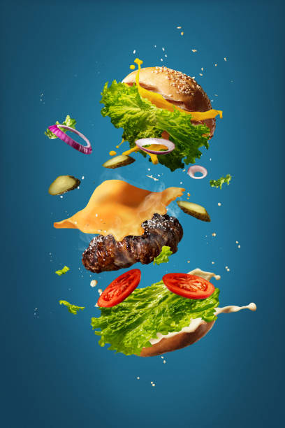 青いスタジオの背景に飛ぶ食材を持つハンバーガー。ファーストフード、料理のコンセプト。 - sandwich food lunch chicken ストックフォトと画像