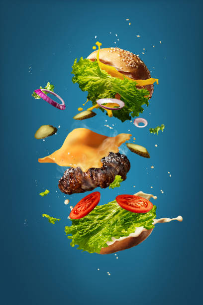 istock Hamburger with flying ingredients on blue studio background. Fast food, cuisine concept. 1306511050