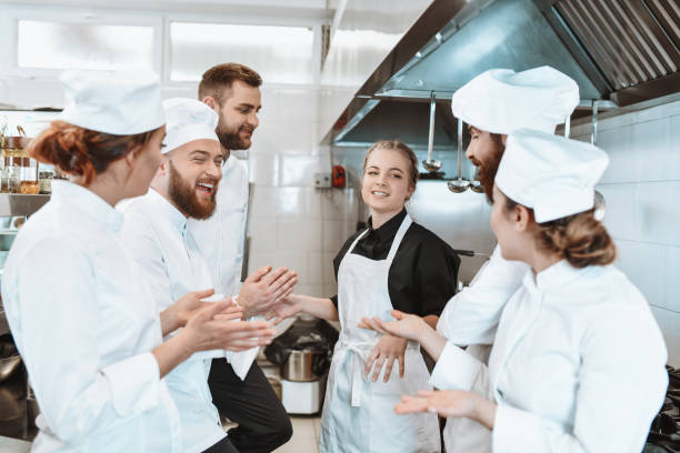 istock Kitchen Team Applauding Female For Winning Cooking Competition 1306512232