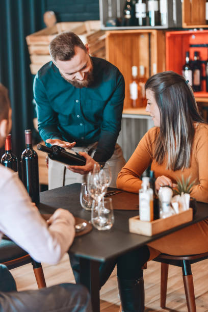 istock Waiter Pouring Fine Wine For Couple In Restaurant 1306512644